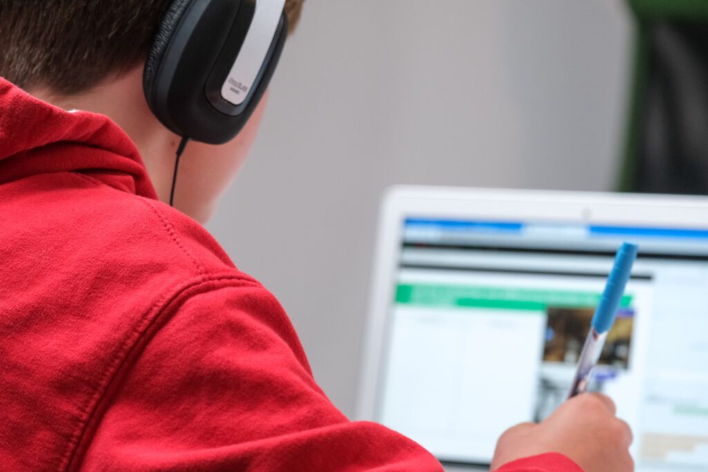 a boy with headphone is studing online with laptop